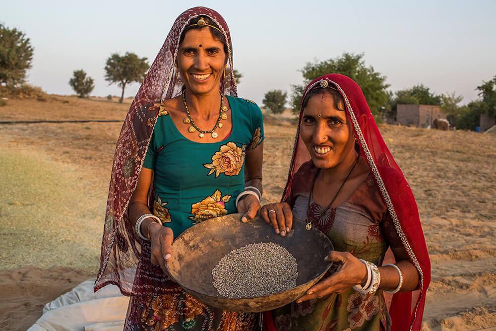 two people holding a container of seeds outside