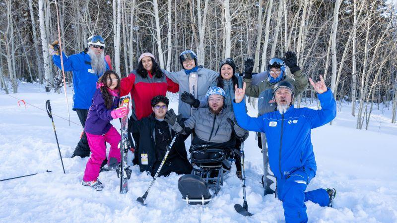 People posing with skis on snowy mountain