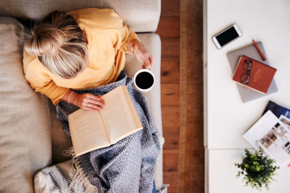 Aerial view of a woman reading a book on a couch