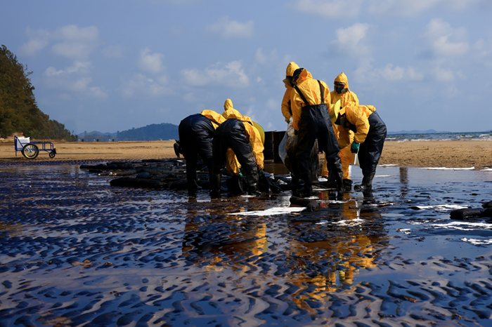 Group of workers cleaning up an oil spill on the beach