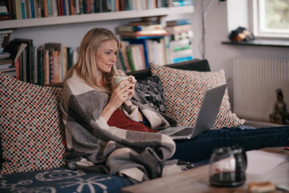 Woman sitting on a couch watching a show on her laptop