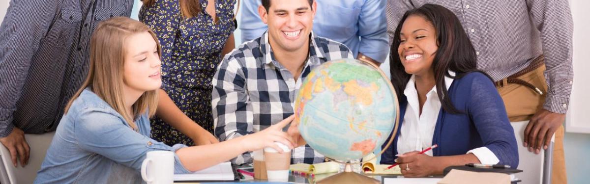 3 people having a discussion around a globe