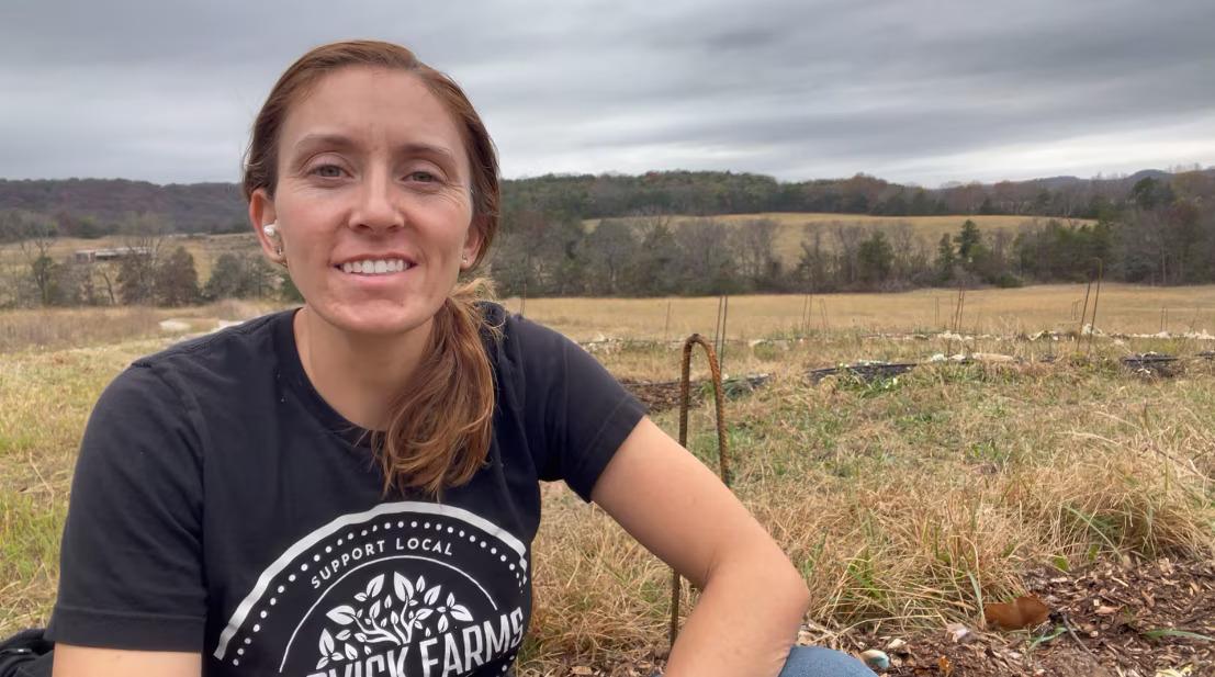 A young person shown in a field on a farm.