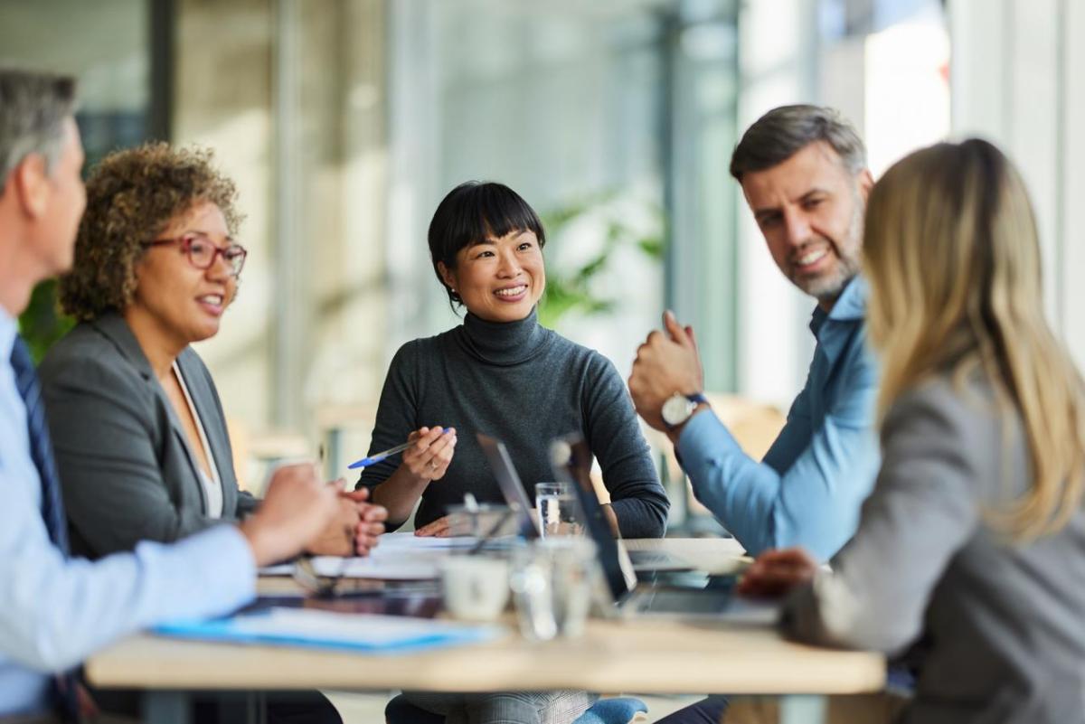 Team of five coworkers sitting around a table and smiling