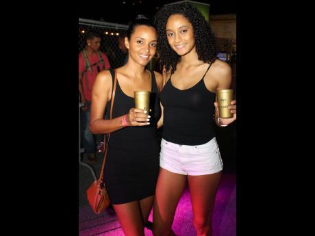 Former Miss Jamaica Sanya Hughes left and her sister Ysabelle, show off the Bacardi 'Green' Cups at the Major Lazer and Friends concert, recently held at the Mas Camp.