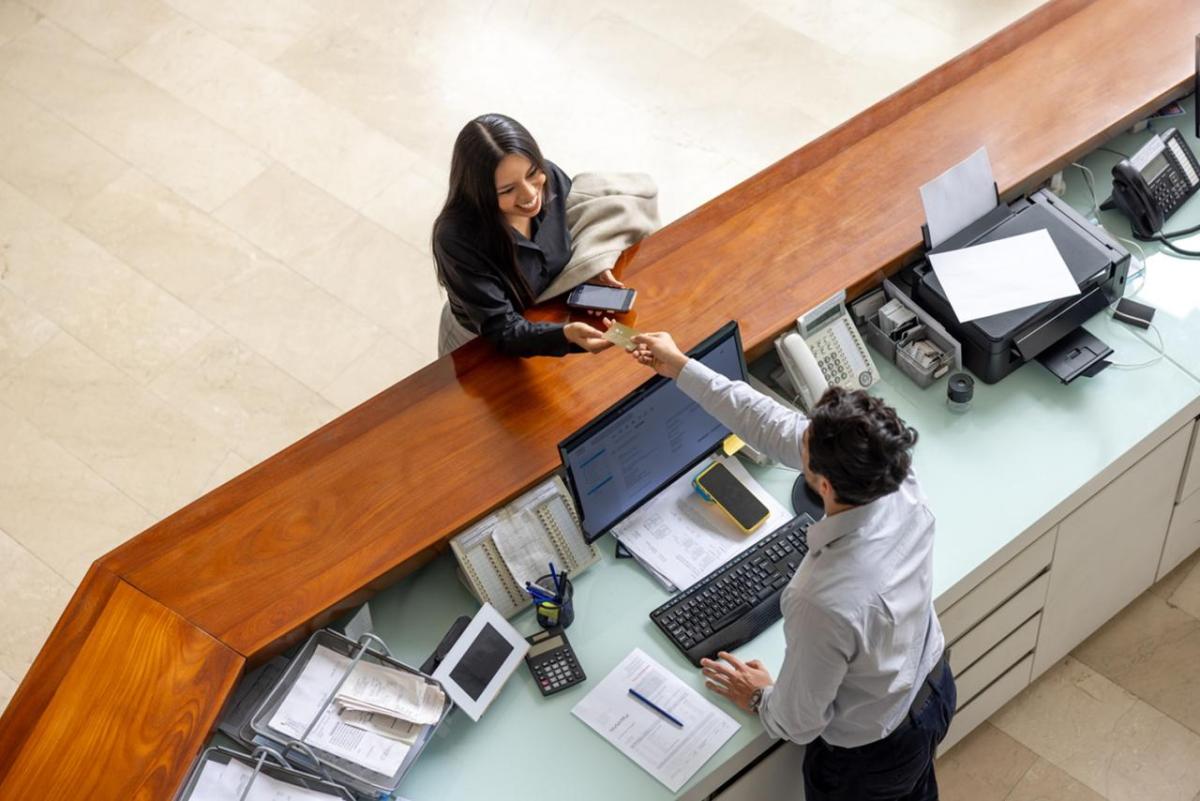 Aerial view of woman paying for hotel stay at front desk