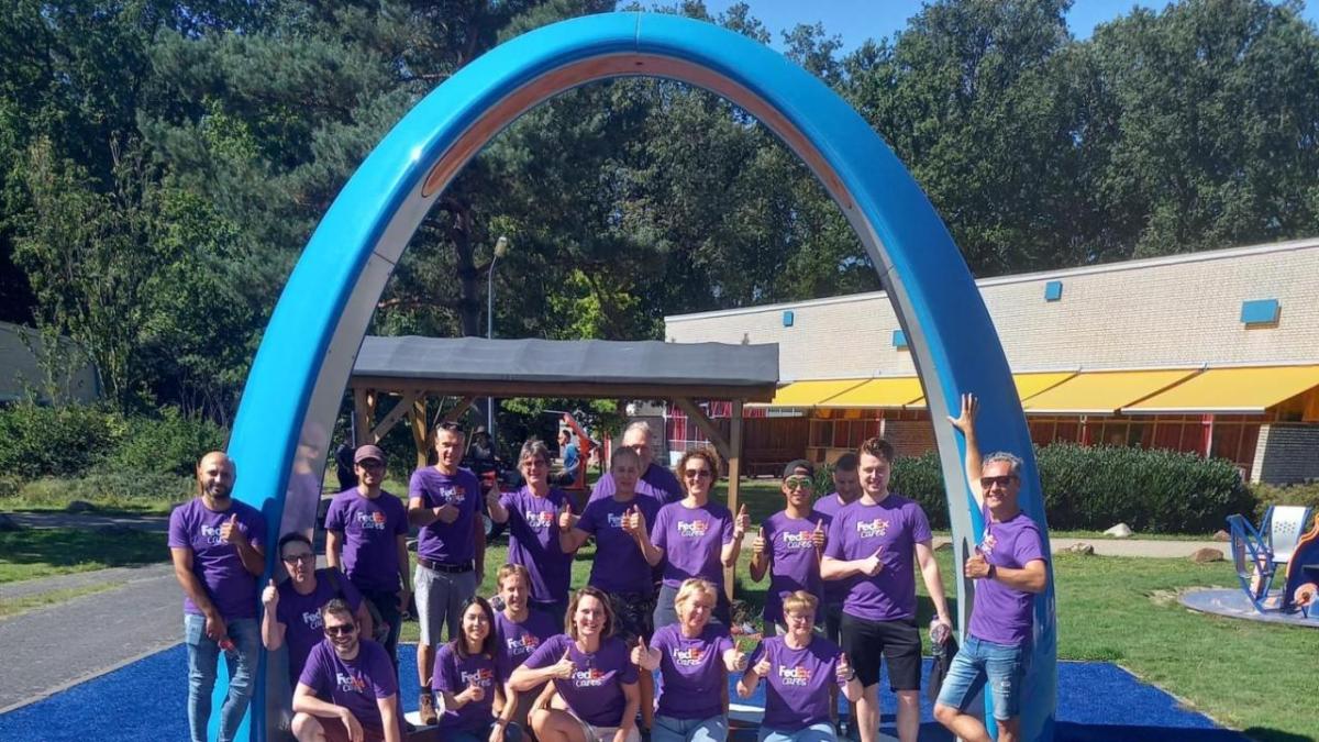 Volunteers posed in front of a large blue arch outside.