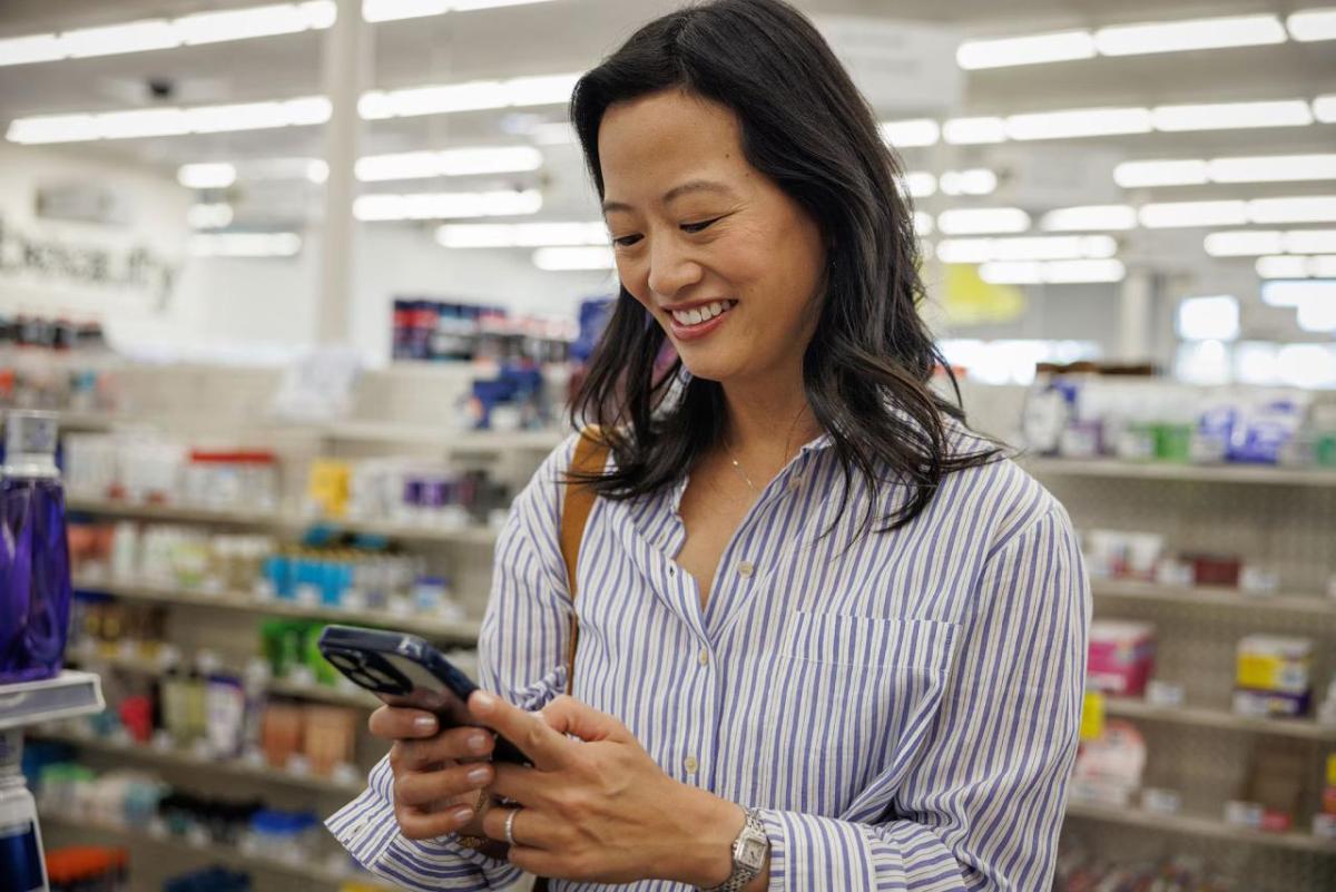 A woman in a CVS using an app on her phone.