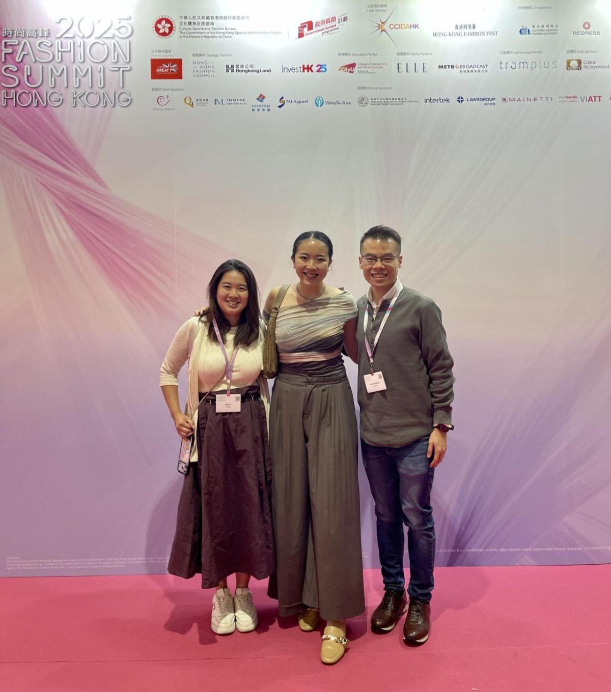 Three people on a stage, red carpet