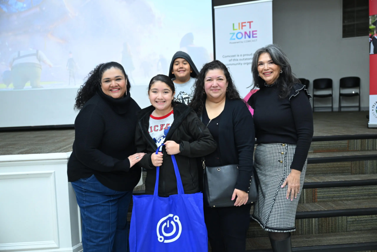 Group photo centering a student who is holding a bag containing the tech tools needed to connect her home to the internet