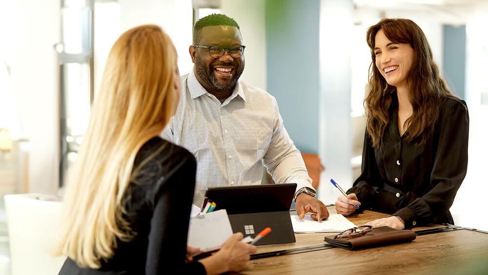 Three people stood at a table having a discussion 