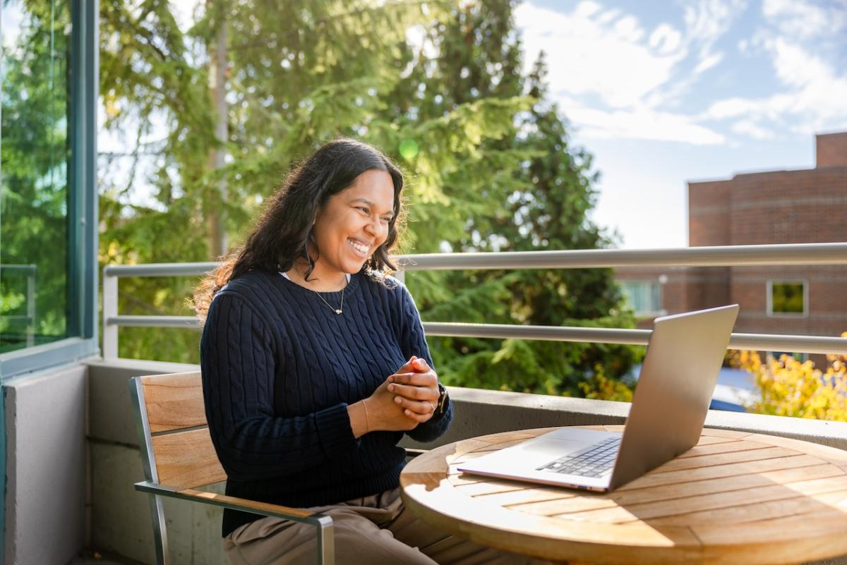 GoDaddy employee sitting outside with a laptop.