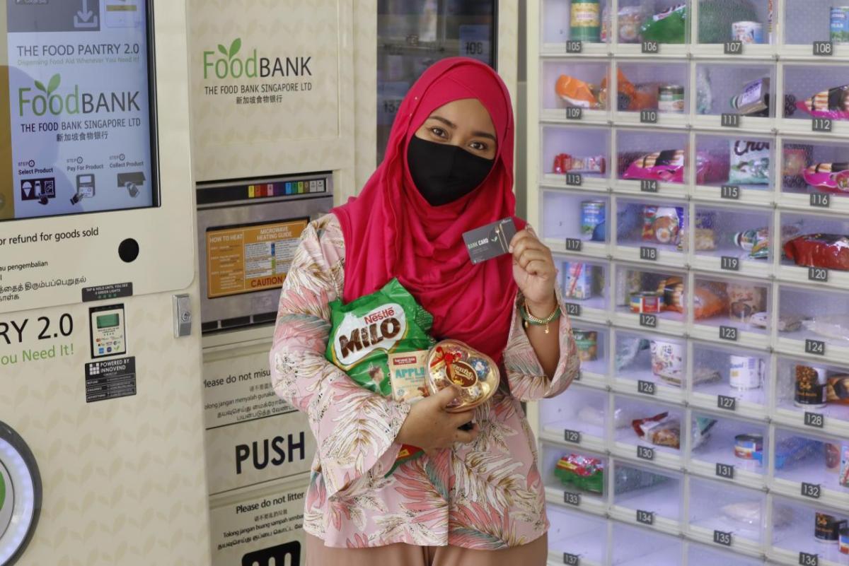 Woman holding up her food bank card