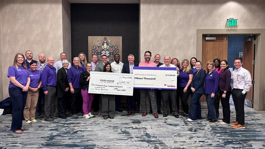 Group photo with two large checks on display for the food bank