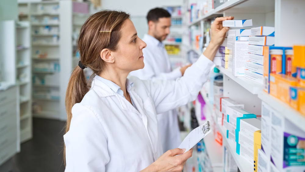 A pharmacist shown stocking medication on a shelf.