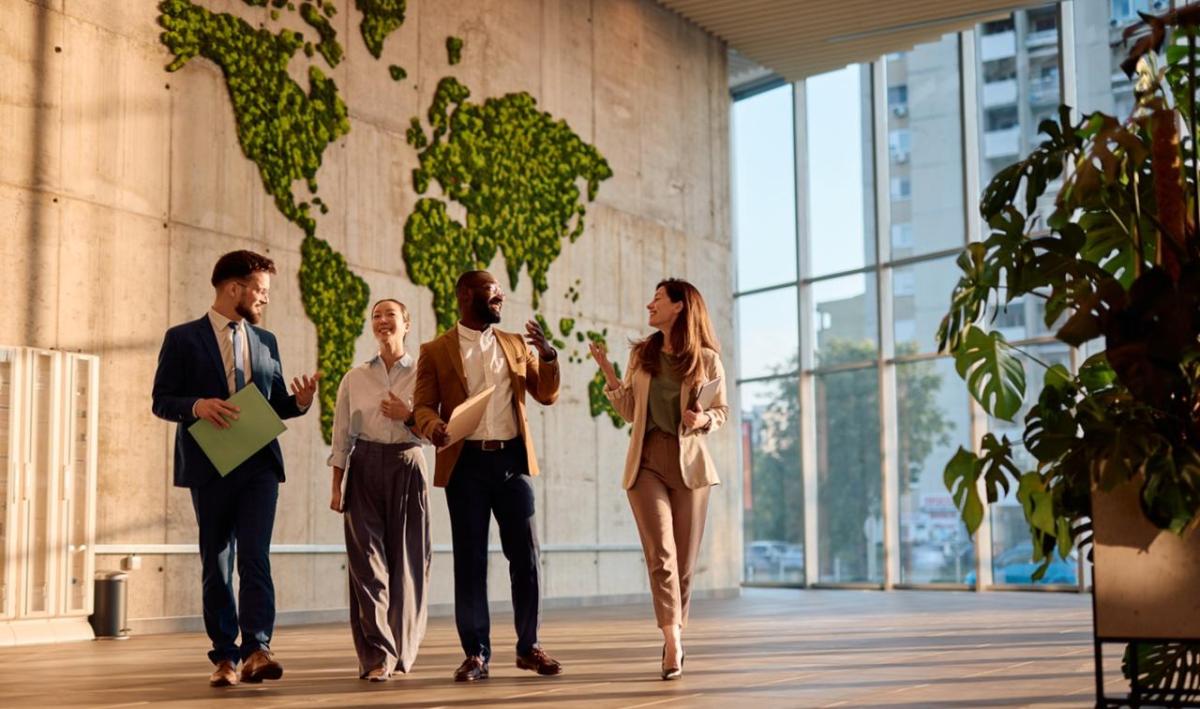 Team walking and chatting in an office building with a map of the world in the background