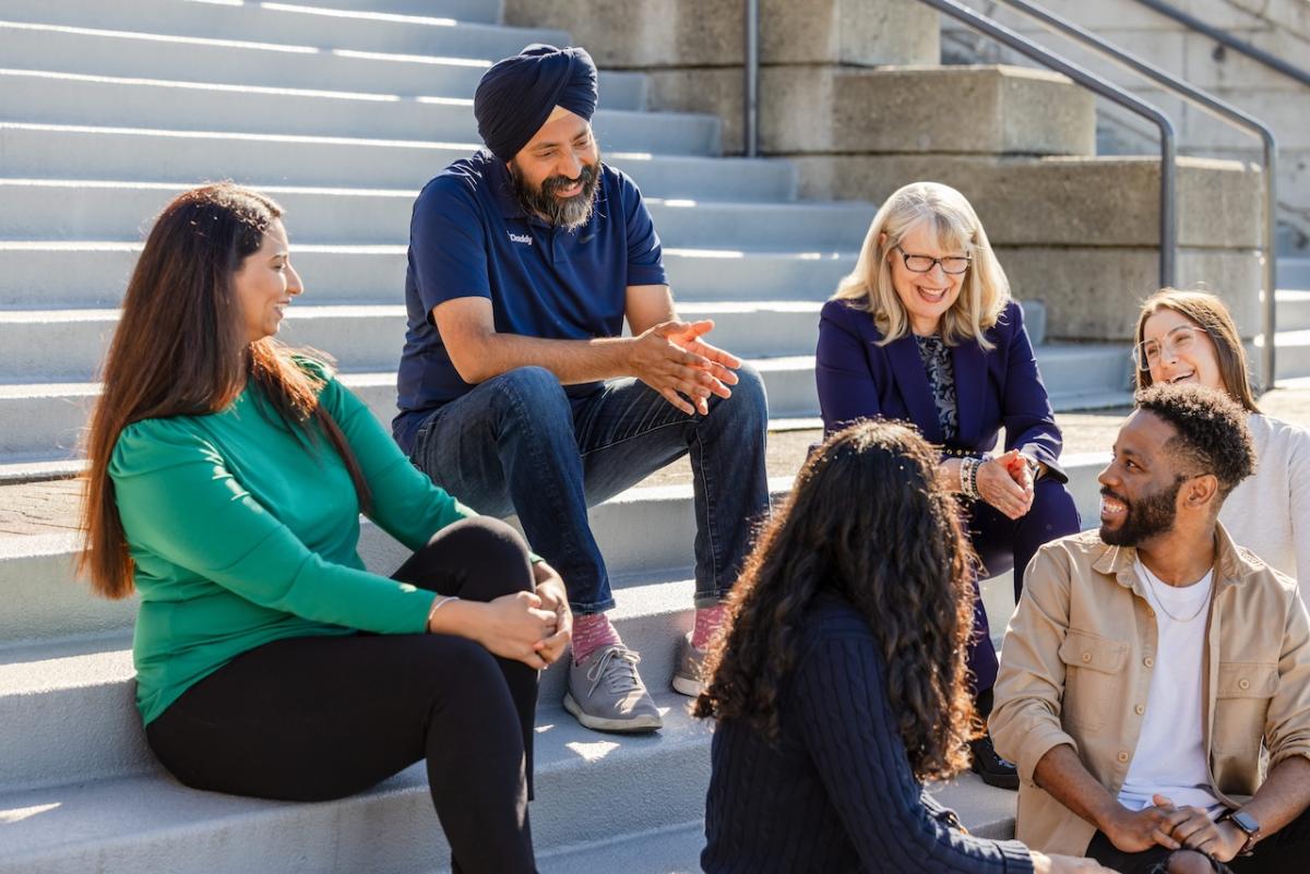 CEO Aman Bhutani shown with a group of people chatting on steps outside of a building.