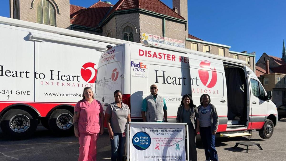Group photo in front of Heart to Heart van and truck