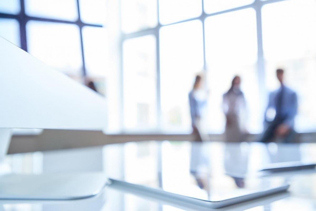 Blurred photo featuring three people in the back of a well-lit office space