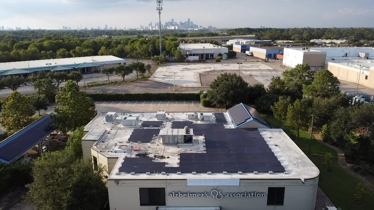 Solar panels on the roof of a building with the Houston skyline in the background