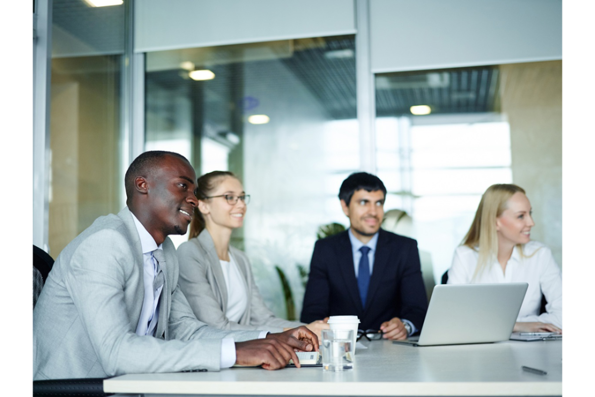 Group of four professionals listening to a presentation in an office