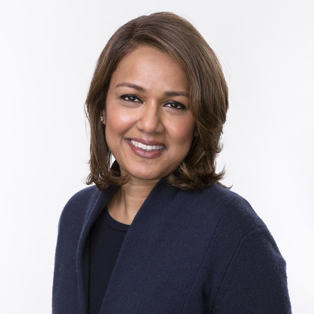Brown haired lady smiling with a navy blue jacket.