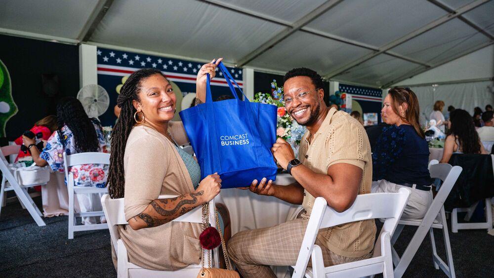 Couple holding up a "Comcast Business" bag at the Operation Shower event 