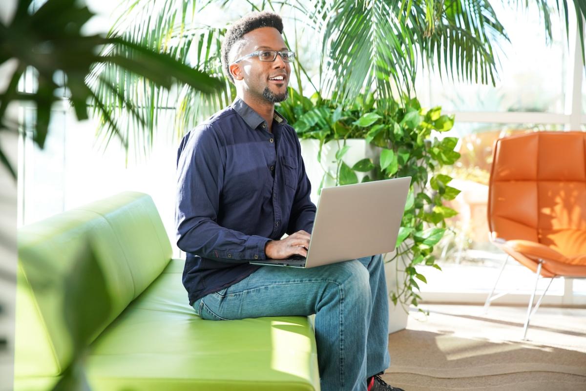 Person seated on a couch with a laptop.