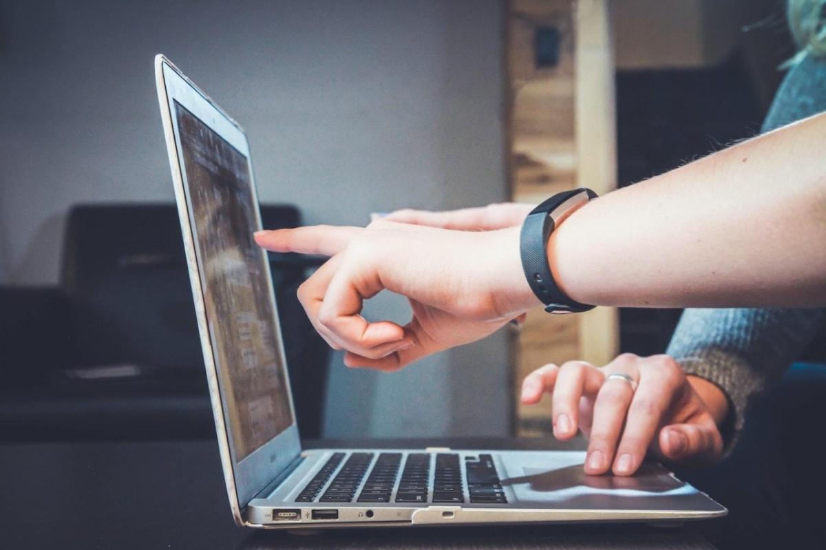 Person touching laptop screen