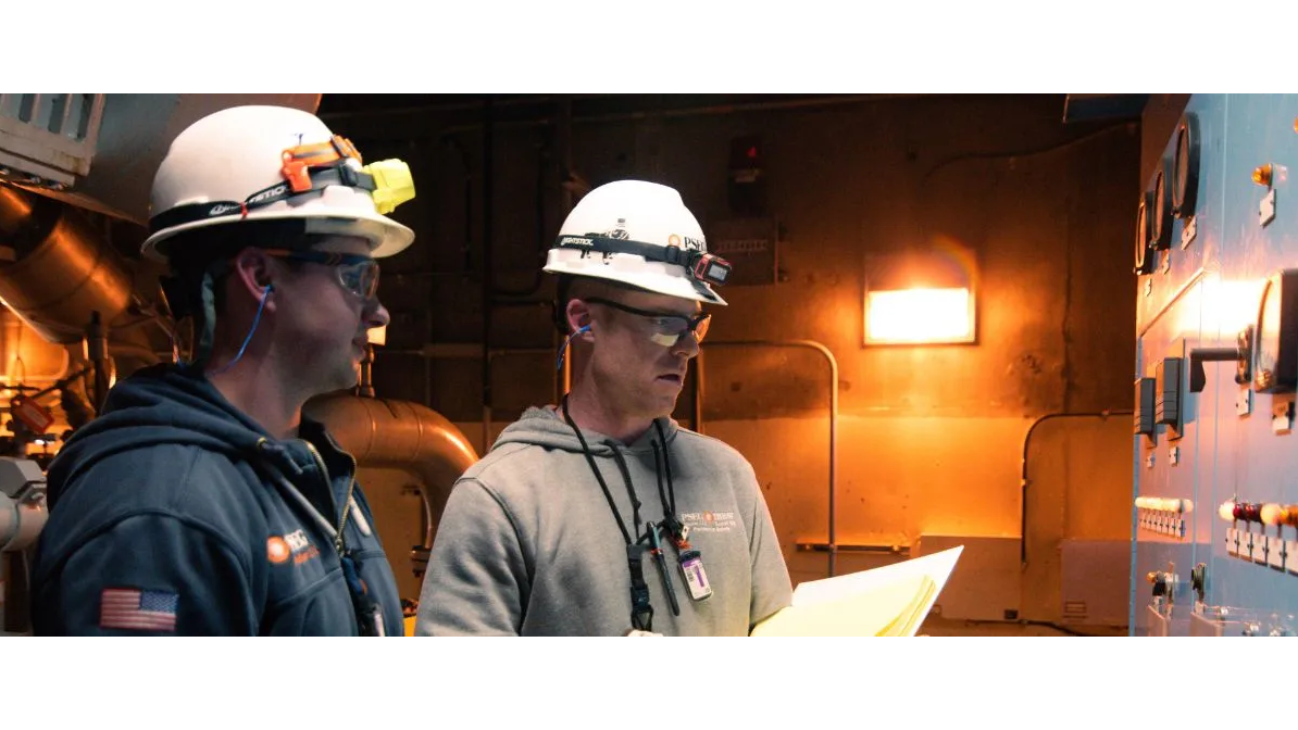 Two people wearing hard hats working in power plant
