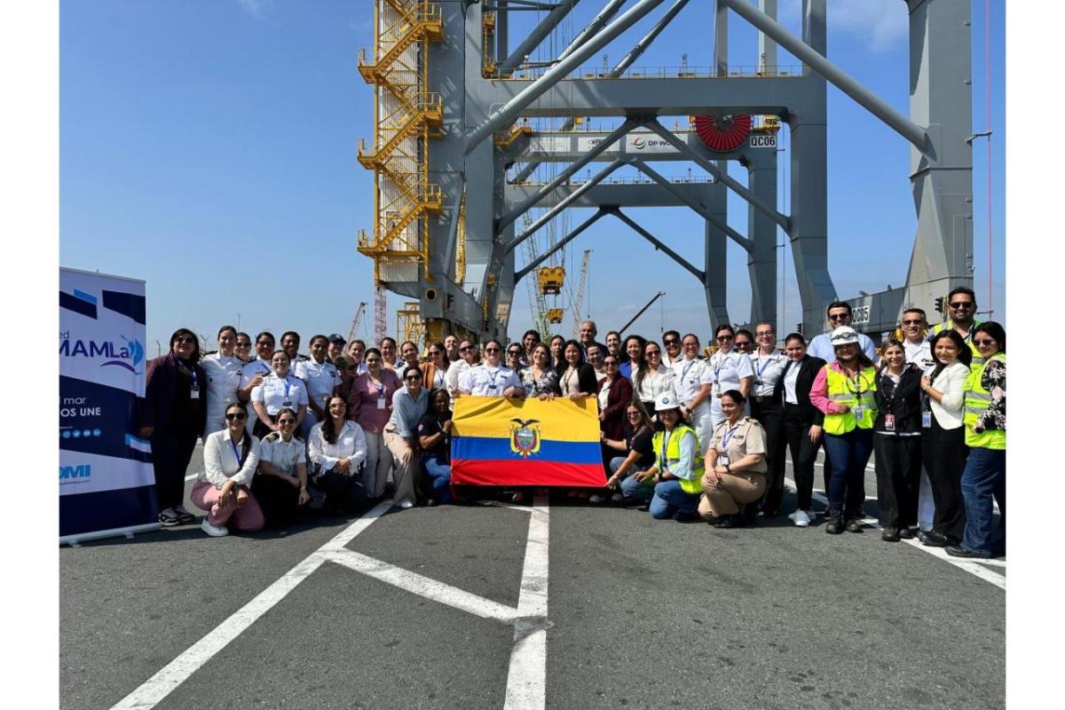 A large group of women and men stand together at a port terminal holding the Ecuadorian flag during a gender equity event with Red MAMLa.