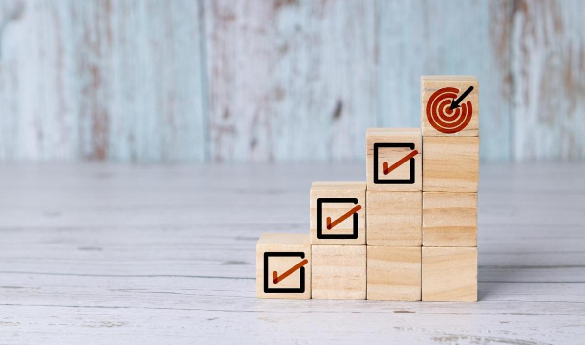 Wooden blocks with checked boxes stacked to mimic four steps