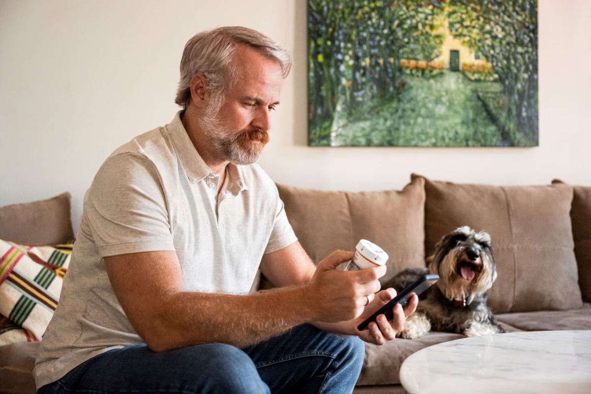 Man looking at medicine bottle while picking up the phone