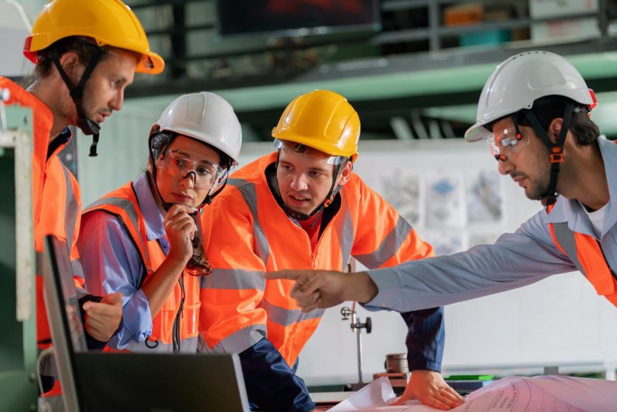 Four EHS professionals in safety gear discussing plans