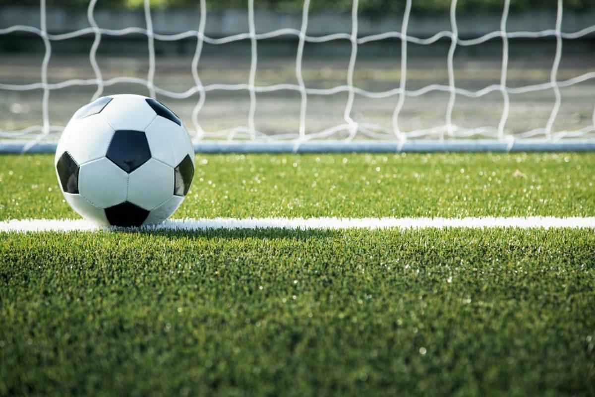 Soccer ball on turf in the foreground with a net in background