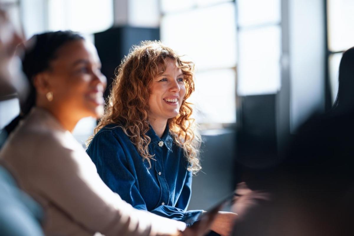 Smiling Colleagues Engaging During an Informal Office Meeting in Brightly Lit Space