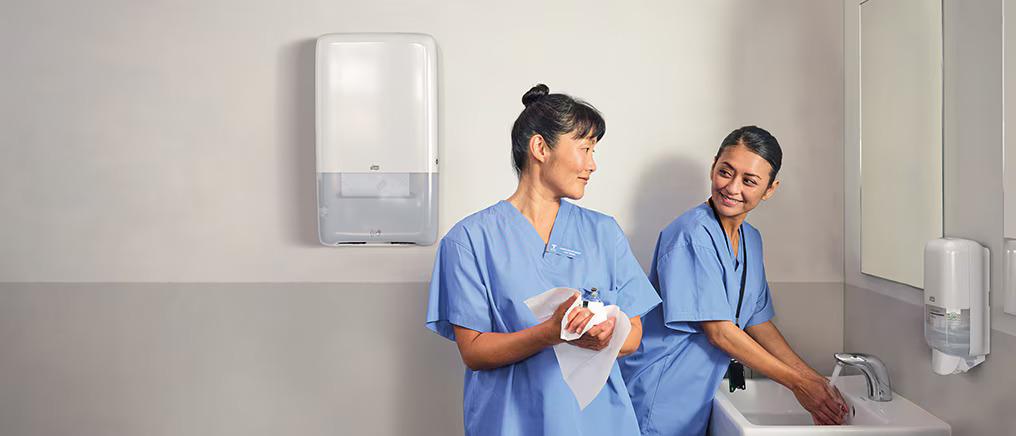 Two healthcare workers washing and drying their hands.
