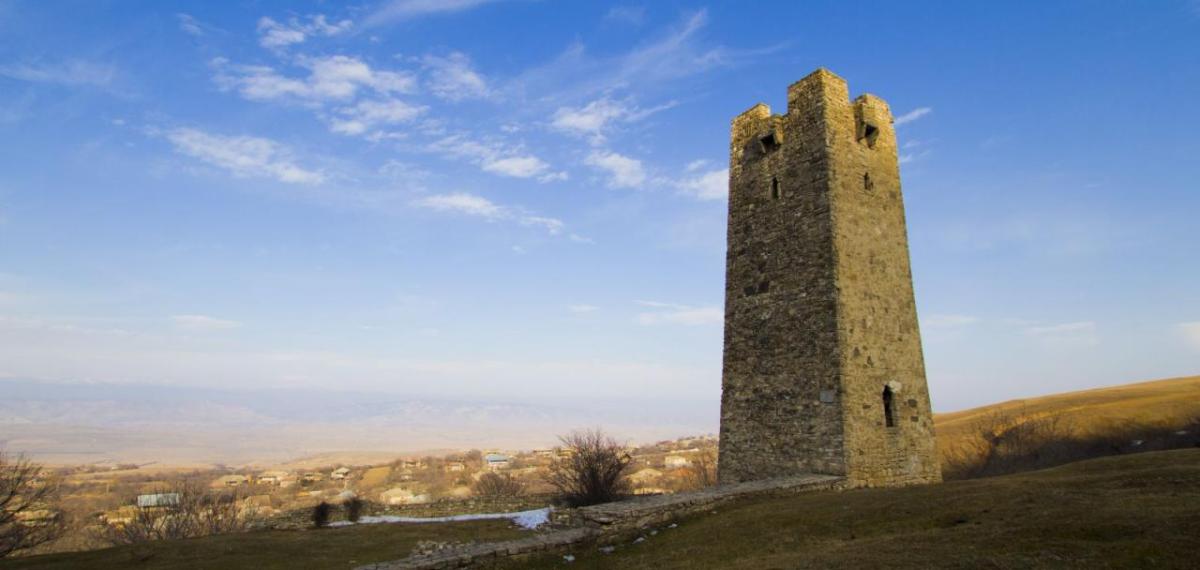 Stone tower shown on top of a hill.