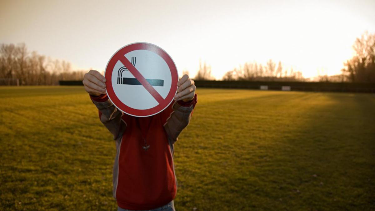 Young adult holding a no smoking sign.