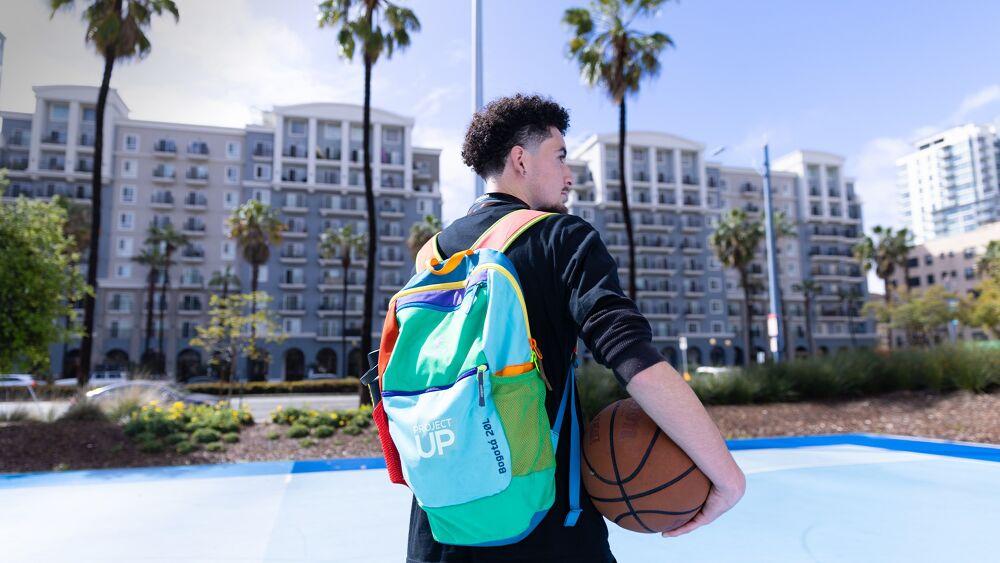 Person with a colorful "Project UP" backpack holding a basketball