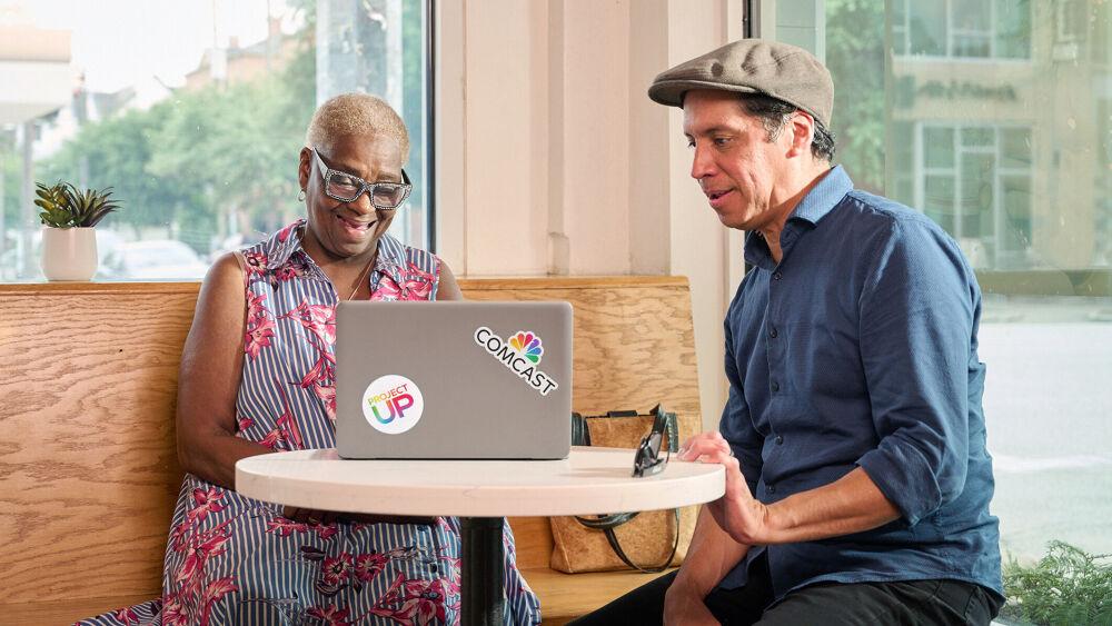Two people sat at a table using a laptop