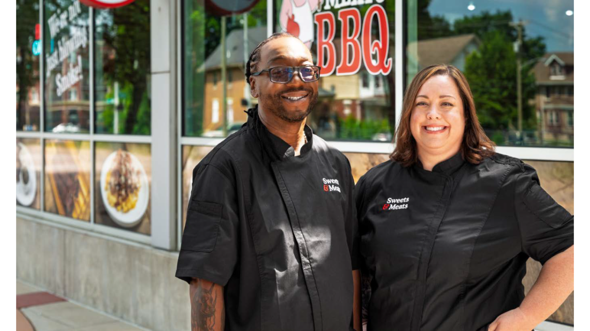 Two people standing in front of a BBQ establishment