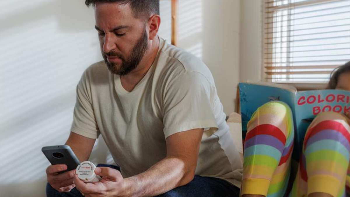 Male patient reading a prescription and looking at his phone.