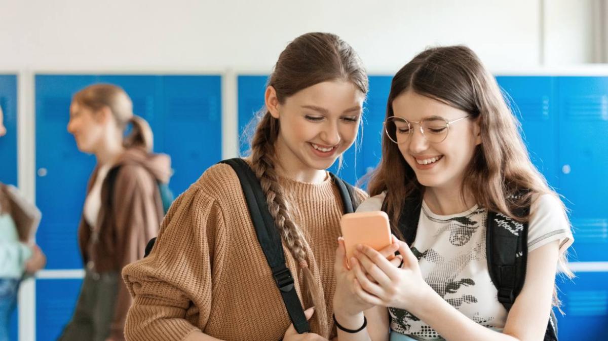 Two teenage girls looking at a phone together 