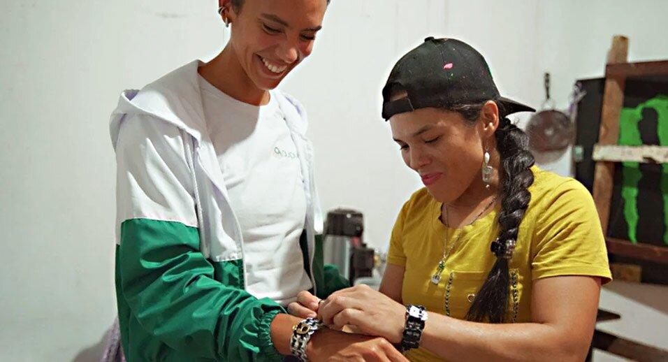 Woman assisting customer in trying on bracelet