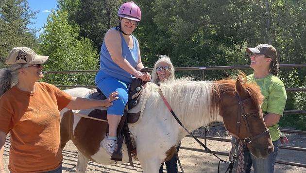 person with special needs riding a horse with support from three other people