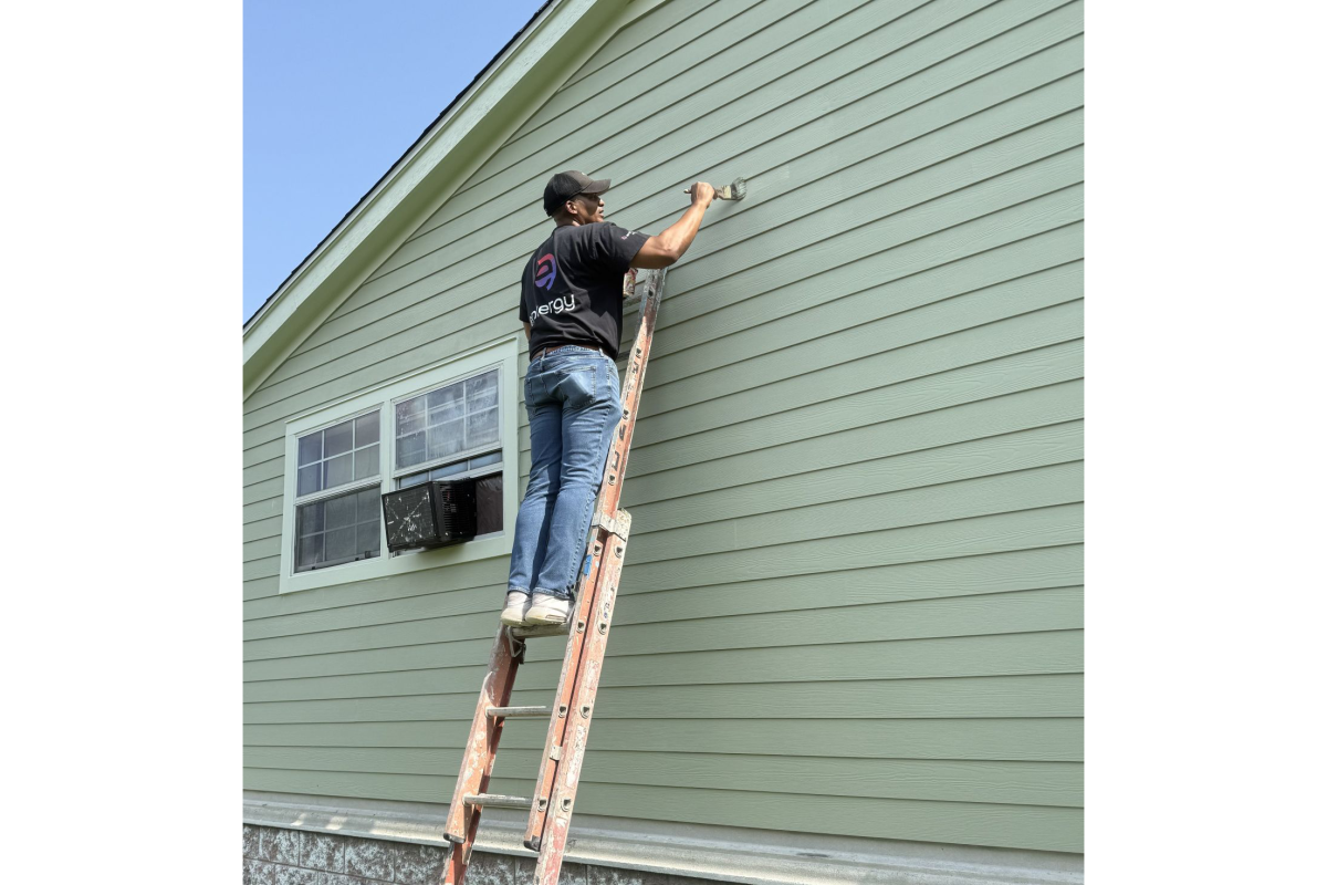 Volunteer on a ladder painting a house exterior