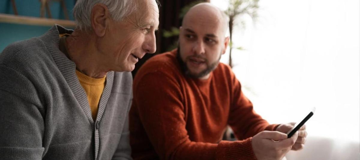 Senior speaking to a younger man about a smartphone