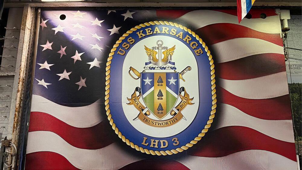 American flag with emblem for USS Kearsarge on top