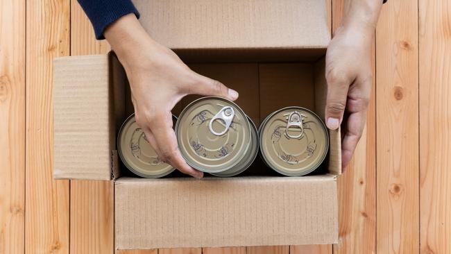 Hands packing canned food into a box
